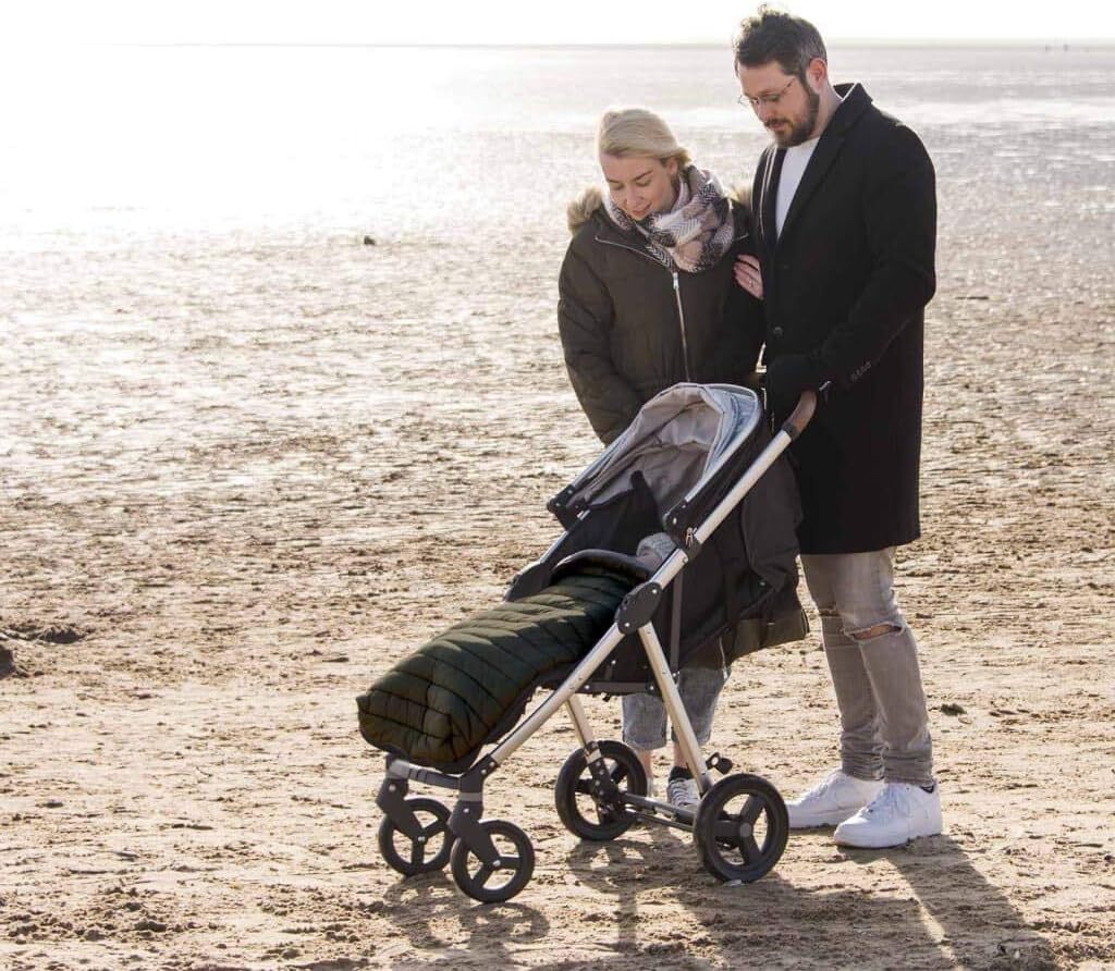 Rodičia na prechádzke s kočíkom a prechodným fusakom CuddleCo